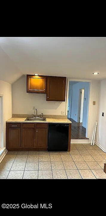 kitchen featuring sink, light tile patterned floors, dishwasher, and vaulted ceiling
