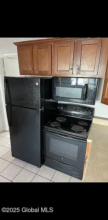 kitchen with light tile patterned floors, backsplash, and black appliances
