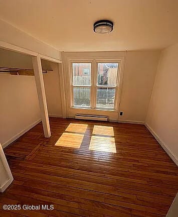 interior space with a baseboard heating unit and dark hardwood / wood-style floors