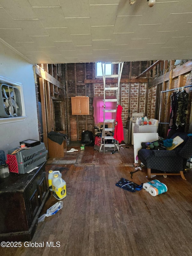 miscellaneous room with dark hardwood / wood-style floors and brick wall