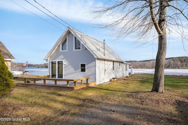 back of house with a deck with water view and a yard