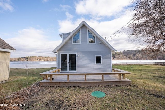 rear view of house with a deck with water view and a yard