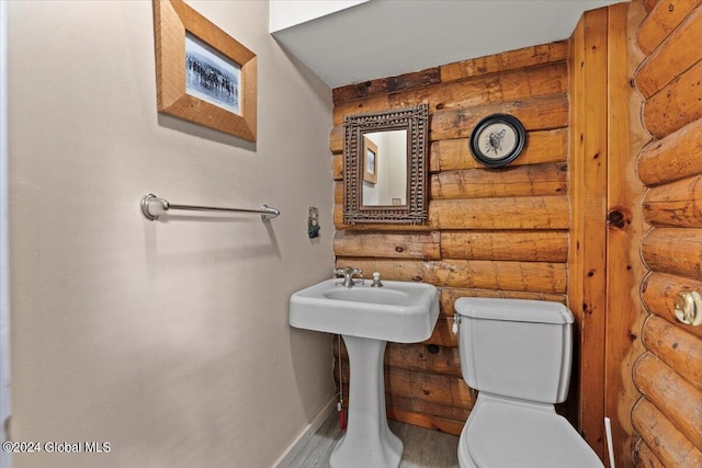 bathroom featuring toilet and log walls