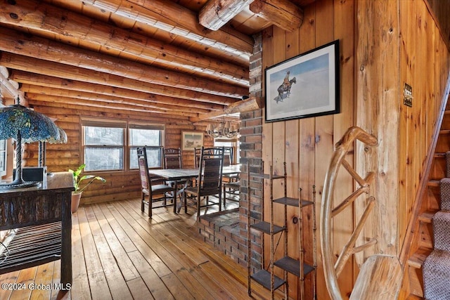 dining space featuring beam ceiling, wood ceiling, hardwood / wood-style flooring, and rustic walls