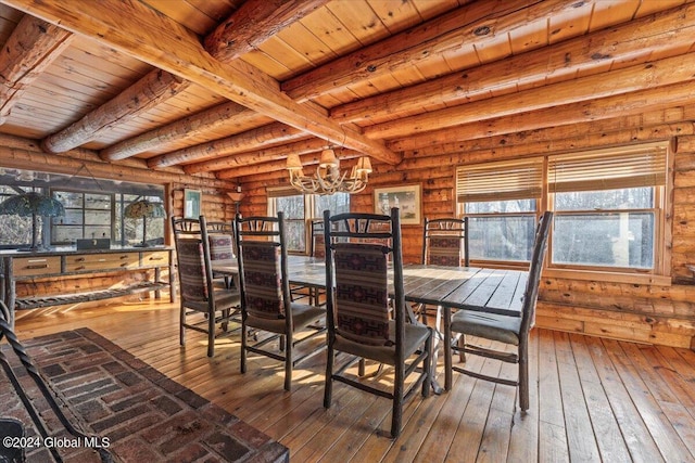 unfurnished dining area with a notable chandelier, beam ceiling, rustic walls, hardwood / wood-style flooring, and wood ceiling