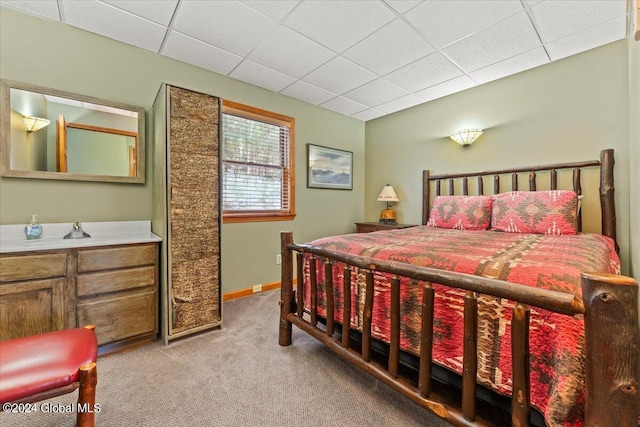 bedroom featuring light carpet and a drop ceiling