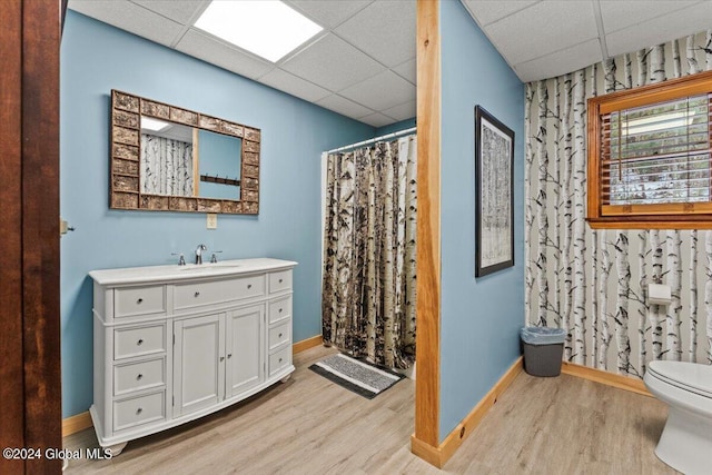 bathroom featuring wood-type flooring, toilet, a paneled ceiling, and vanity