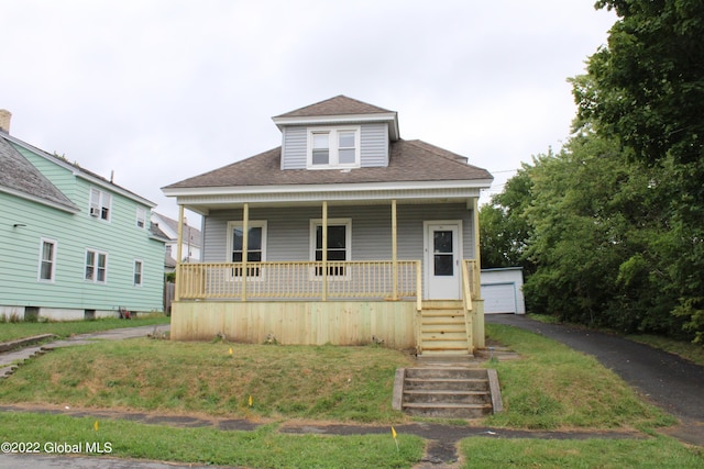 bungalow-style home with a garage, a front yard, an outbuilding, and covered porch