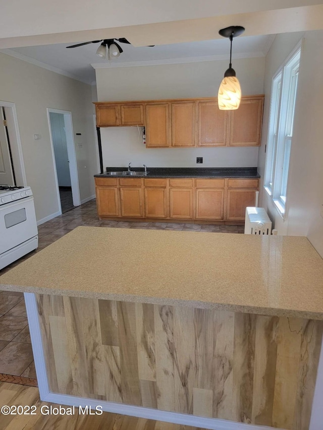 kitchen featuring pendant lighting, gas range gas stove, a center island, ceiling fan, and crown molding