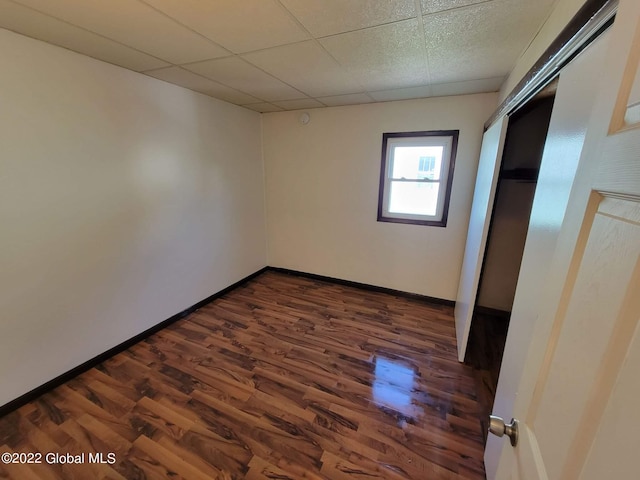 spare room featuring dark hardwood / wood-style flooring and a paneled ceiling