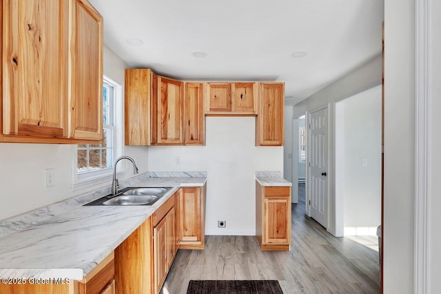 kitchen with light stone counters, sink, and light hardwood / wood-style floors