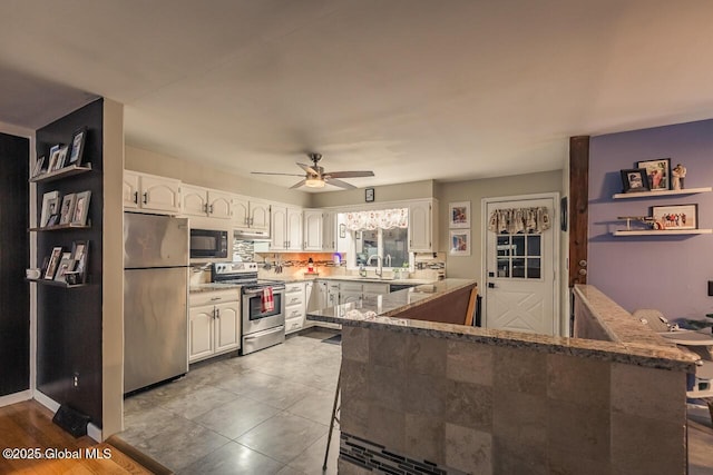 kitchen featuring ceiling fan, stainless steel appliances, kitchen peninsula, and white cabinets