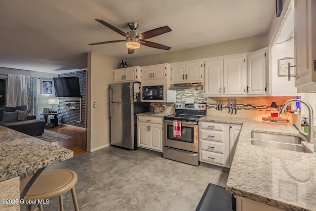 kitchen featuring appliances with stainless steel finishes, tasteful backsplash, sink, white cabinets, and light stone counters