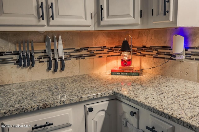 kitchen featuring white cabinetry, light stone counters, and backsplash