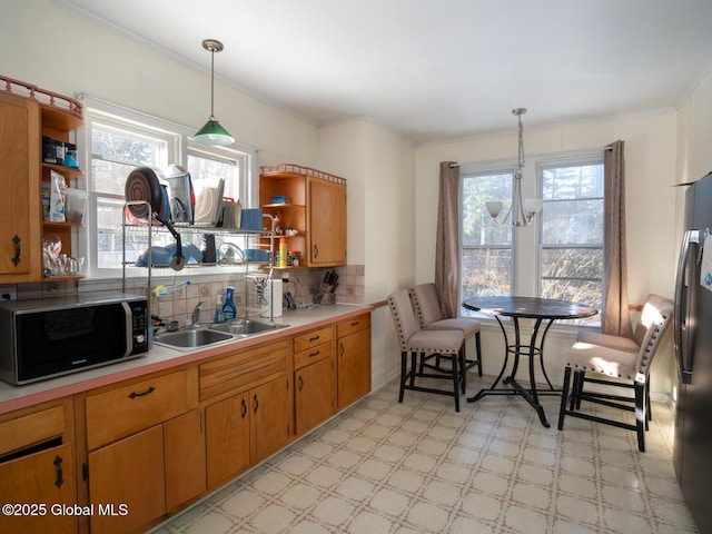 kitchen with pendant lighting, a wealth of natural light, sink, and stainless steel refrigerator