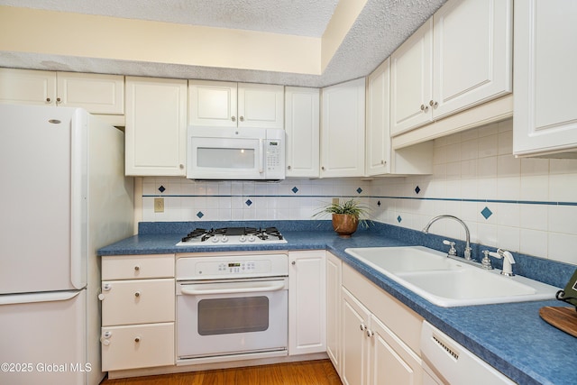 kitchen featuring backsplash, white cabinets, white appliances, a textured ceiling, and a sink