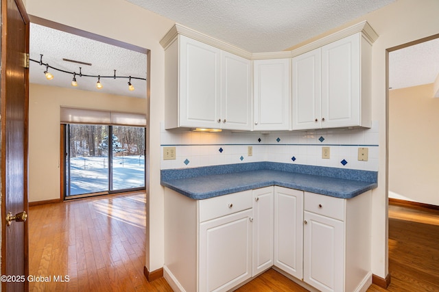 kitchen with tasteful backsplash, dark countertops, and light wood finished floors