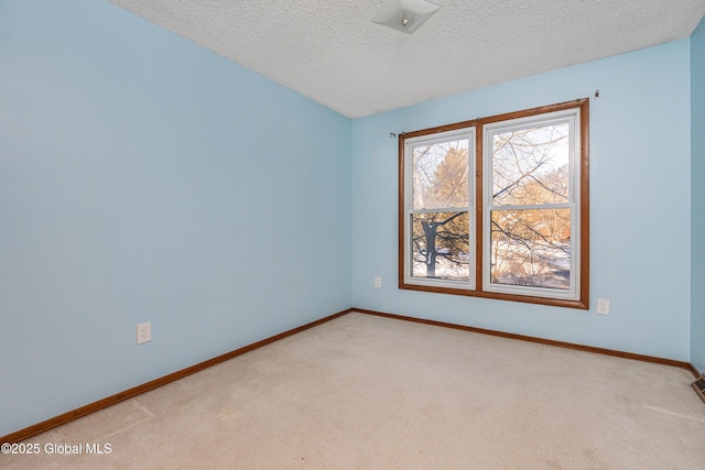 carpeted empty room featuring baseboards and a textured ceiling