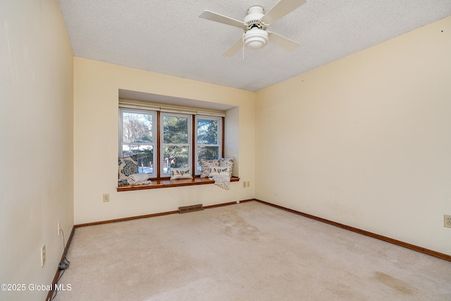 carpeted spare room with visible vents, baseboards, a textured ceiling, and ceiling fan