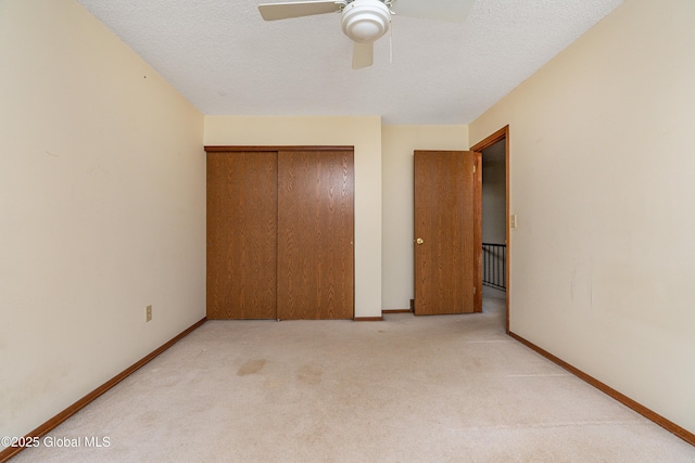 unfurnished bedroom featuring a textured ceiling, light colored carpet, a closet, and baseboards