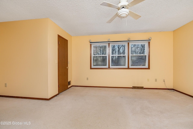 unfurnished room featuring visible vents, light colored carpet, a textured ceiling, and baseboards