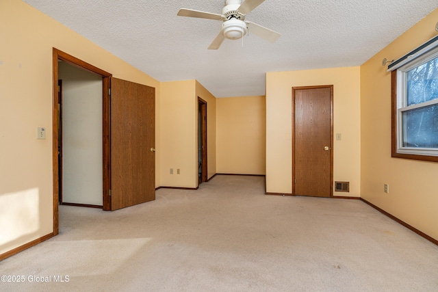 spare room with a textured ceiling, baseboards, visible vents, and light carpet