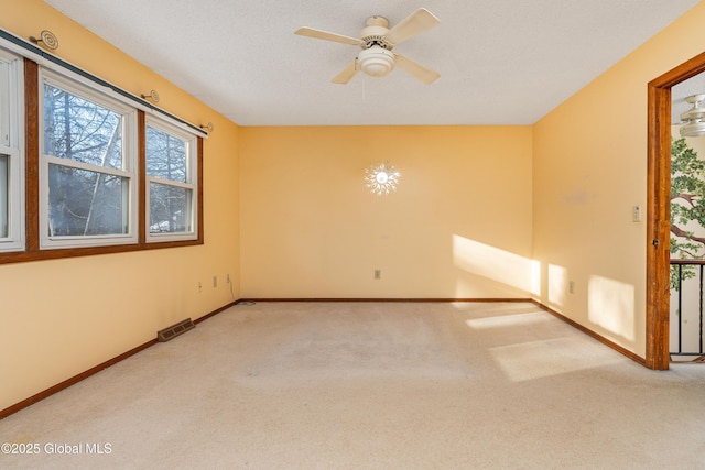 unfurnished room featuring carpet flooring, baseboards, visible vents, and ceiling fan