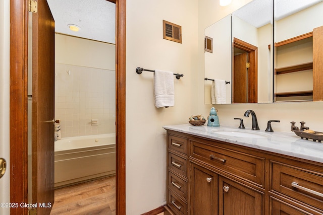 bathroom with vanity,  shower combination, wood finished floors, and visible vents