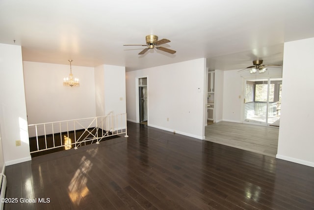 unfurnished living room with ceiling fan with notable chandelier, dark wood-type flooring, and a baseboard radiator