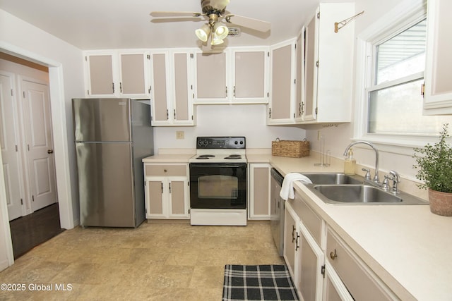 kitchen with appliances with stainless steel finishes, sink, white cabinets, and ceiling fan