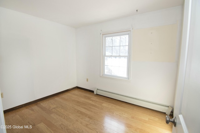 empty room featuring baseboard heating and light hardwood / wood-style flooring