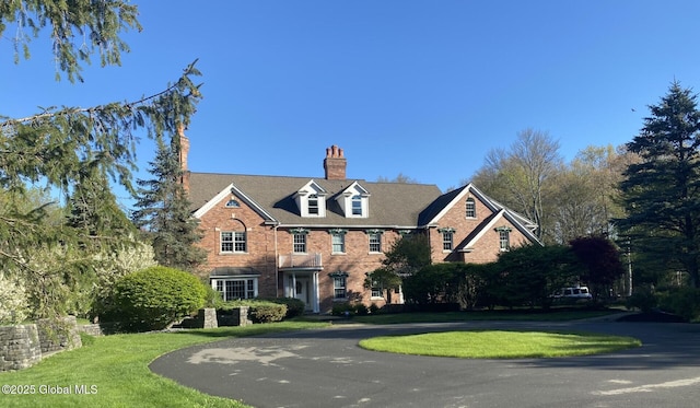 georgian-style home featuring driveway, brick siding, and a front yard