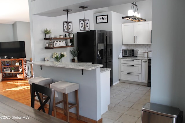 kitchen with tasteful backsplash, a breakfast bar, hanging light fixtures, and white cabinets