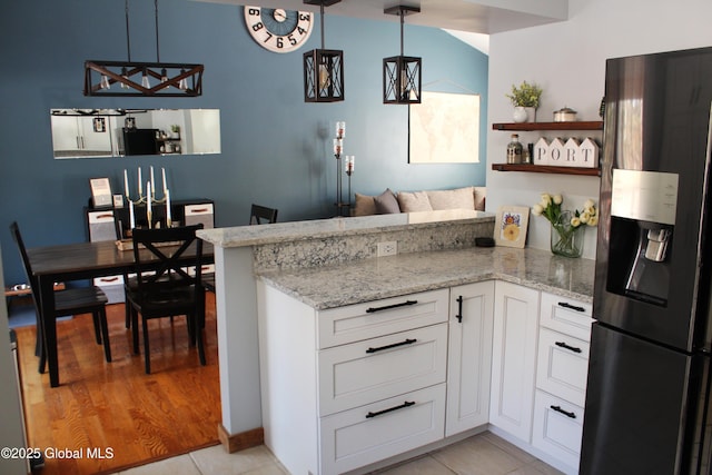 kitchen featuring stainless steel refrigerator with ice dispenser, light tile patterned flooring, white cabinetry, hanging light fixtures, and kitchen peninsula