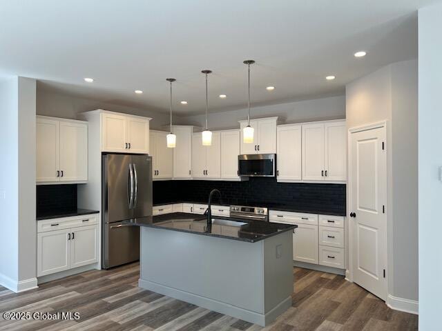 kitchen featuring decorative light fixtures, white cabinetry, a center island with sink, and stainless steel appliances