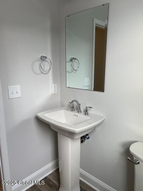 bathroom featuring toilet, wood-type flooring, and sink