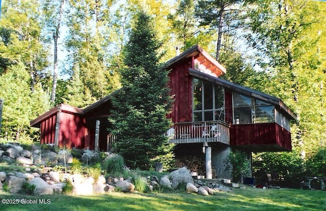 rear view of property featuring a sunroom and a lawn