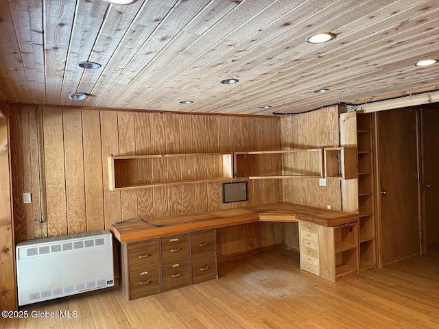 unfurnished office with built in study area, radiator, wood ceiling, light wood-type flooring, and wood walls