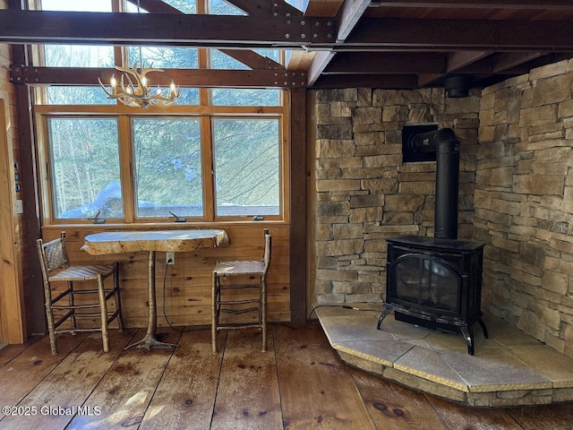 interior space featuring a wood stove, a notable chandelier, beam ceiling, and hardwood / wood-style flooring