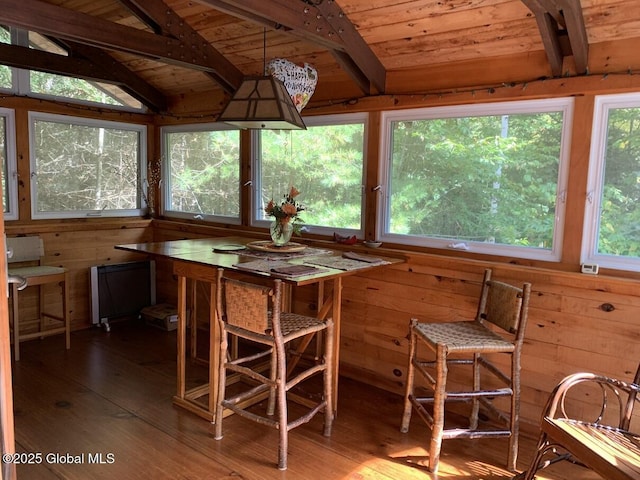 unfurnished dining area featuring lofted ceiling with beams, hardwood / wood-style floors, wood ceiling, and wooden walls