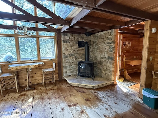 interior space with a wood stove, hardwood / wood-style flooring, beamed ceiling, and wood walls