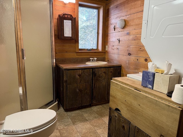 bathroom with a stall shower, wooden walls, toilet, and vanity