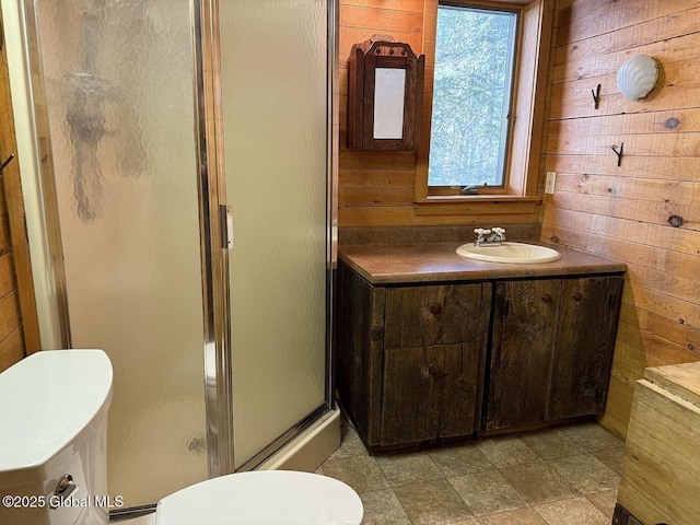 bathroom with vanity, wood walls, a shower stall, and toilet