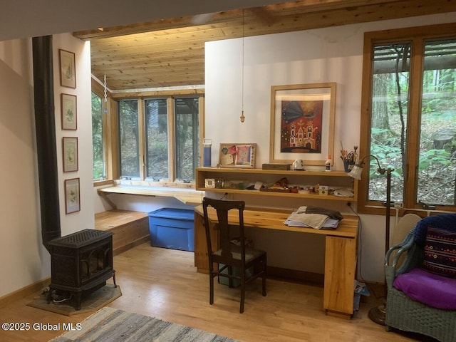 office area with baseboards, lofted ceiling, wood ceiling, wood finished floors, and a wood stove