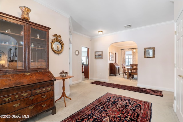 entryway with ornamental molding and light carpet