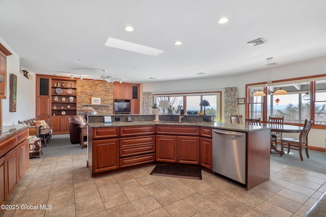 kitchen with sink, dishwasher, a skylight, decorative light fixtures, and dark stone counters