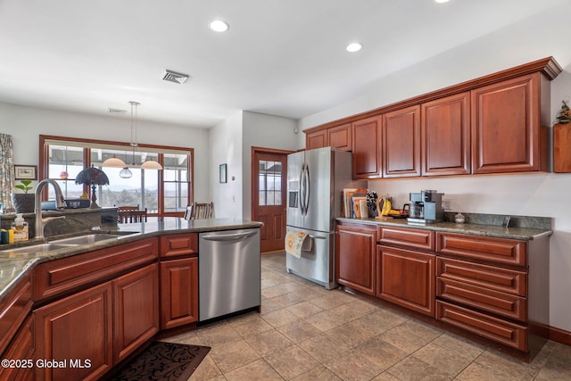 kitchen with appliances with stainless steel finishes, sink, dark stone counters, hanging light fixtures, and an inviting chandelier