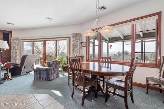 carpeted dining area with beam ceiling