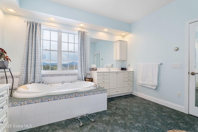 bathroom featuring a relaxing tiled tub and vanity