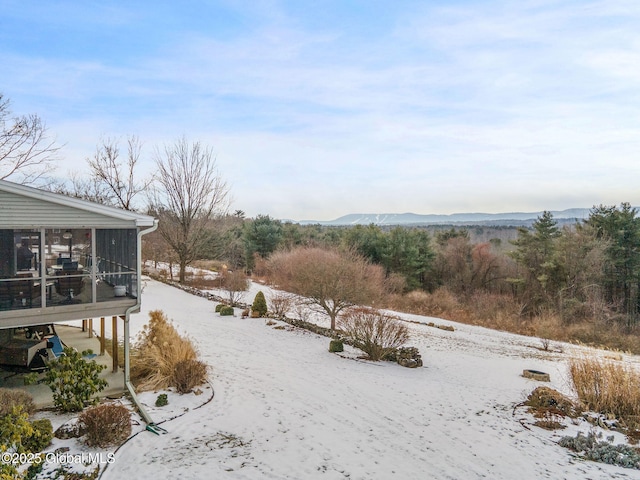 snowy yard with a mountain view and a sunroom